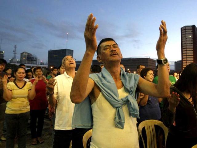 Filipino Catholics raise their arms during prayers as they attend the first dawn Mass at the Cultural Center of the Philippines building in Manila. AP