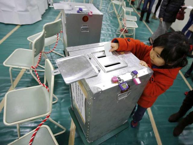 Haruka Tobe casts a ballot for her parents at a polling station located inside an elementary school in Tokyo. Reuters
