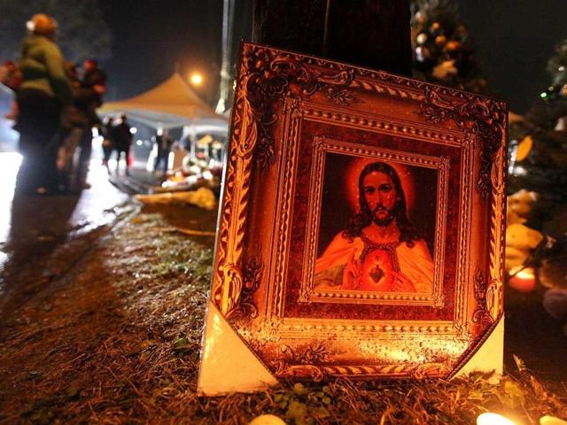 People gather near a Jesus painting at a memorial for victims of the mass shooting at Sandy Hook Elementary School in Newtown, Connecticut. AFP Photo