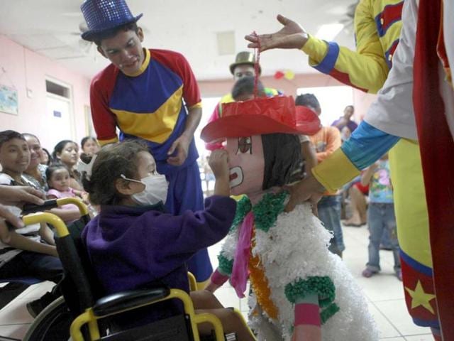 Surrounded by clowns, a patient touches a "pinata," a decorated figure containing toys and candy, at the oncology area of the La Mascota Children Hospital in Managua, Nicaragua. AP photo