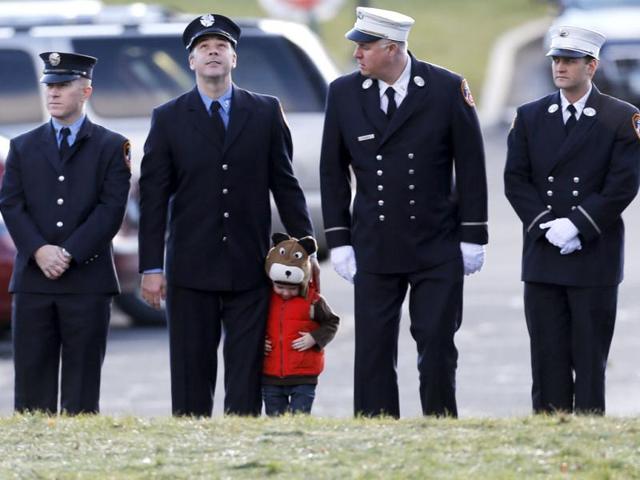 A child lines up with firefighters outside the funeral for school shooting victim Daniel Gerard Barden at St. Rose of Lima Catholic Church in Newtown, Connecticut. AP Photo