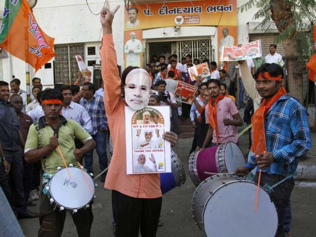 BJP supporter wears a mask of Gujarat chief minister Narendra Modi as he celebrats to early reports stating their party is leading in the Gujarat Assembly elections in Ahmedabad. Supporters of the right-wing Bharatiya Janata Party (BJP) set off firecrackers and waved flags in delight as Modi performed the hat-trick in the state. (AP Photo)