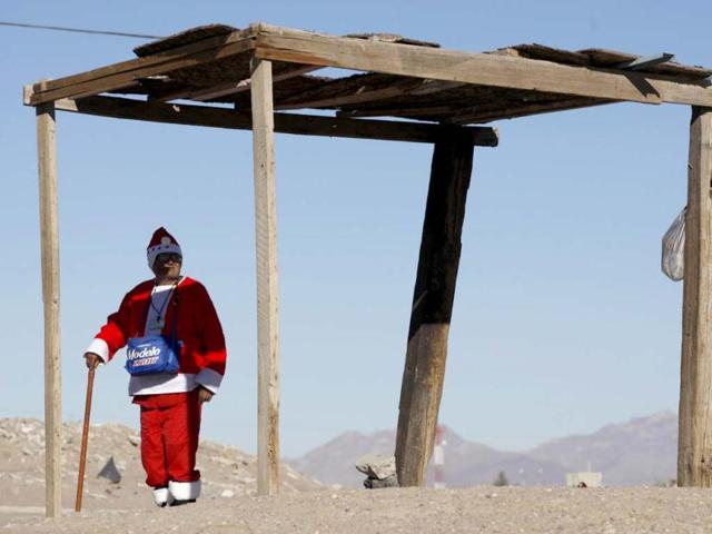 Antonio Martinez, 78, stands in the shade dressed in an old Santa Claus costume while waiting for buses on the outskirts of Ciudad Juarez. Martinez boards the buses and asks for money in return for some candy. Martinez is trying to get enough money so he can buy a toy truck for his grandson for Christmas, according to a local newspaper. Reuters/Jose Luis Gonzalez
