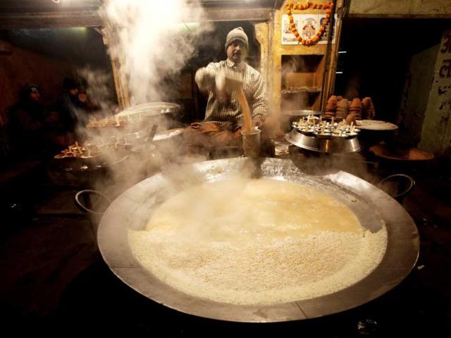A local shop owner warms milk to sell to passengers waiting for trains in Allahabad. Thick fog has been affecting flight and train movement with some trains reportedly running over 15 hours late. (AP Photo)