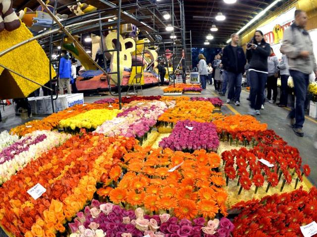 A tour group walks past flowers as they wait to be applied to Honda's "Follow Your Dreams" Rose Parade float in Pasadena, Calif. The Rose Parade is scheduled for January 1, 2013. (AP Photo)