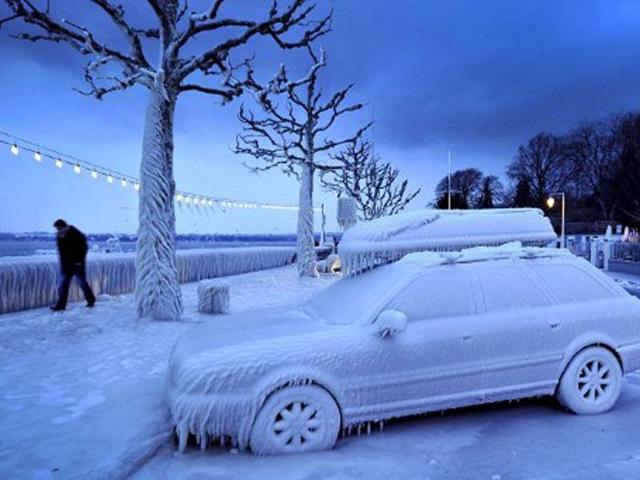 A man walks past an ice covered car on the frozen waterside promenade at Lake Geneva in the city Versoix, near Geneva in early February. AFP/Fabrice Coffrini
