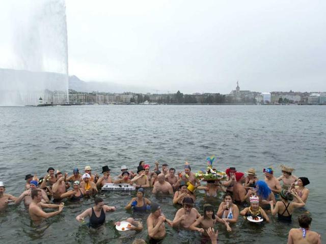 People carry glasses of champagne while swimming in the chilly water during the annual swim in Lake Geneva, on New Year's day. AP Photo