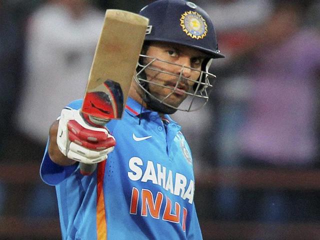 Yuvraj Singh raises his bat after his half century during the first ODI cricket match against England in Rajkot. PTI/Shirish Shete