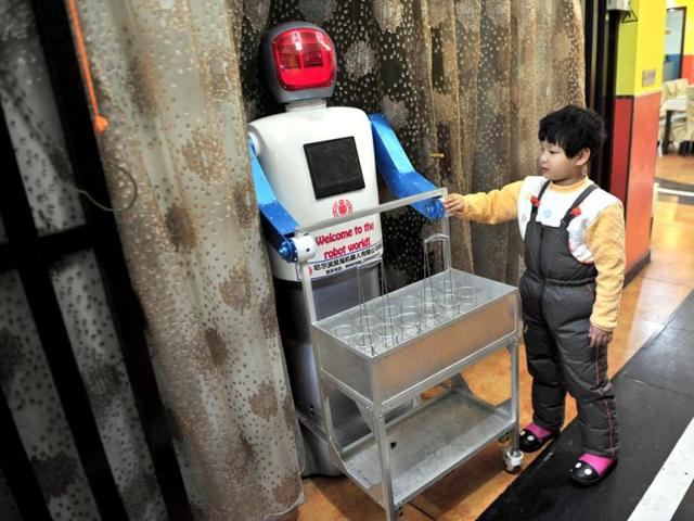 A boy touches a robot that specialises in delivering drinks at a Robot Restaurant in Harbin. Reuters