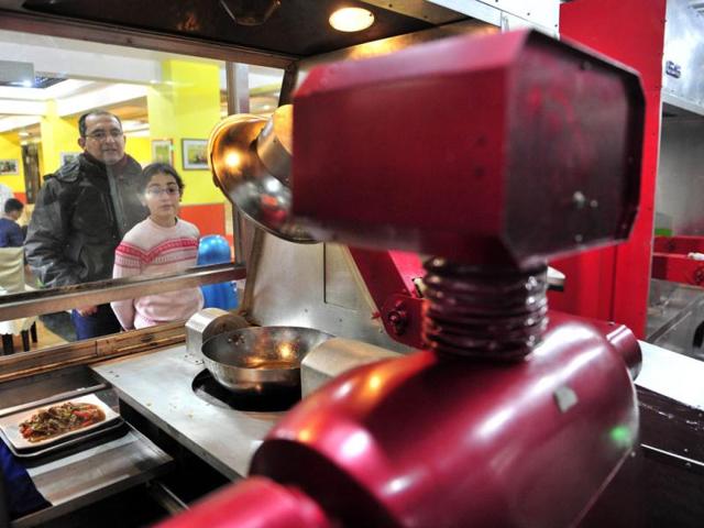 Customers watch a robot cooking dishes at a Robot Restaurant in Harbin. The robots can work continuously for five hours after a two-hour charge, and are able to display over 10 expressions on their faces and say basic welcoming sentences to customers, local media reported. Reuters Photo
