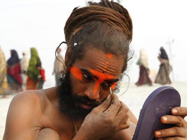 A sadhu applies colour on his face at the bank of Sangam ahead of Maha Kumbh Mela (festival), in Allahabad. Photo by Arvind Yadav/Hindustan Times