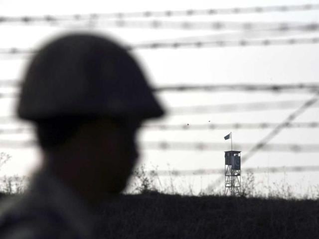 A Border Security Force (BSF) soldier patrols the fenced border with Pakistan against the backdrop of a Pakistani tower in Suchetgarh, southwest of Jammu. Reuters/Mukesh Gupta