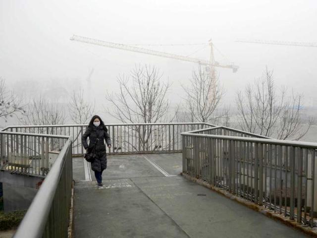 A woman wearing a face mask walks over a footbridge in Beijing. Residents across northern and eastern China battled through heavy smog as extremely high pollution levels shrouded for the second time in about two weeks. (AFP Photo)