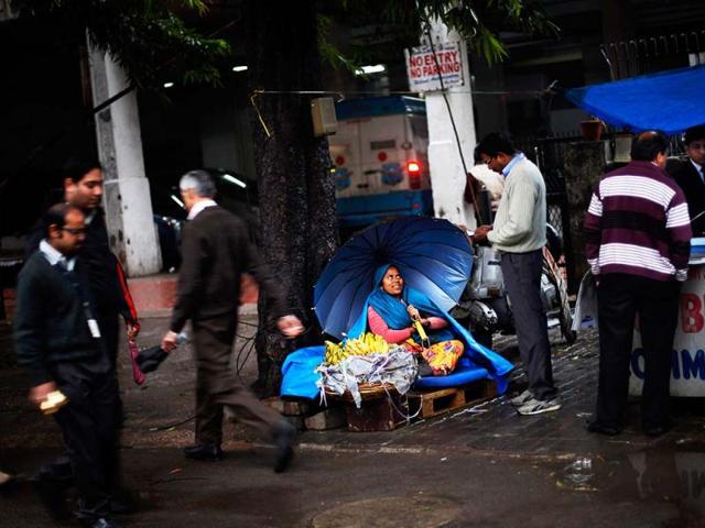A roadside vendor holds an umbrella as she talks to a customer while it rains in New Delhi. AP/Altaf Qadri