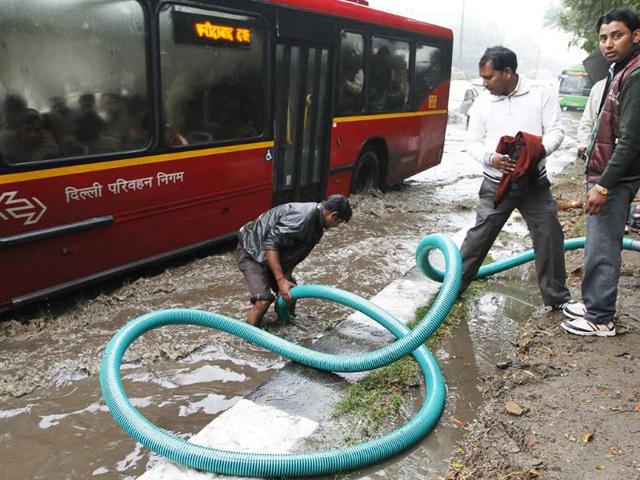A municipal worker unclog drains near a bus stop in New Delhi. HT/Arvind Yadav