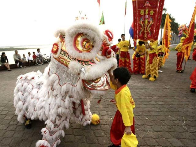 A boy touches a lion dancer as ethnic Cambodian Chinese community people perform a dragon dance in front of the Royal Palace ahead of Lunar New Year, in Phnom Penh, Cambodia. (AP Photo)