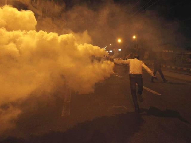 A protester, who opposes Egyptian President Mohamed Mursi, throws a tear gas canister, which was thrown earlier by the riot police, during clashes in front of the presidential palace in Cairo. REUTERS