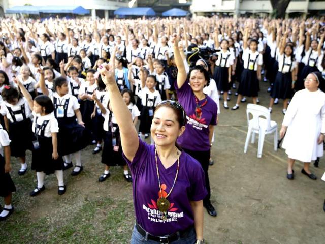 Filipino theater artist Monique Wilson flashes the No.1 sign with students from St. Scholastica's College, an all-girls' school, as they dance at their campus in a global kickoff campaign dubbed One Billion Rising, to end violence against women and children on Valentine's Day in Manila, Philippines.(AP Photo)