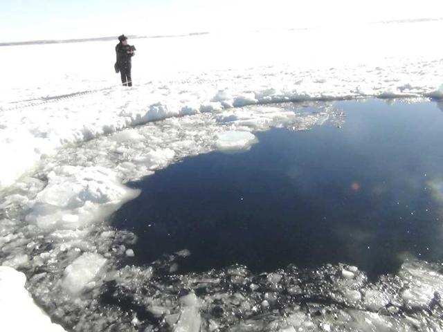 A Russian policeman works near an ice hole, which is said to be the point of impact of a meteorite seen earlier in the Urals region, at lake Chebarkul some 80 kilometers (50 miles) west of Chelyabinsk as per the Interior Ministry department for Chelyabinsk. (Reuters)