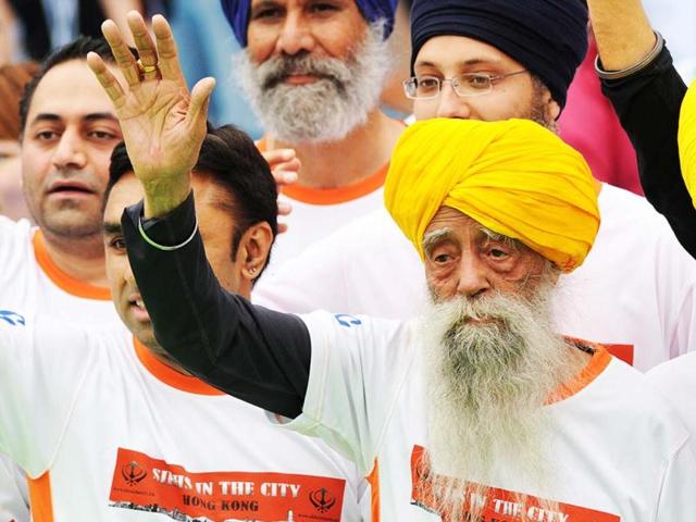 Indian-born British national Fauja Singh, 101 (R) waves to the media after crossing the finish line in the 10-km event as part of the Hong Kong Marathon. Singh retired from competitive races after the marathon. AFP photo