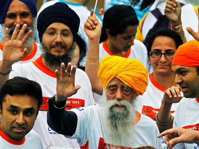 Marathon runner Fauja Singh, 101, center, originally from Beas Pind, in Jalandhar, now living in London, waves after finishing a 10-kilometer race, which was part of the annual Hong Kong Marathon. AP photo