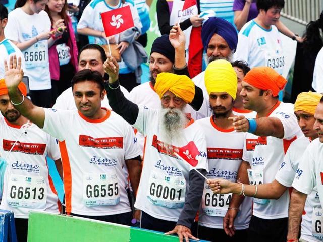 British Indian marathon runner Fauja Singh (C), 101, carrying a Hong Kong flag, and accompanied by other runners wave to fans after finishing the 10-kilometer race of the Hong Kong Marathon. Singh retired from competitive races after the marathon. Reuters photo