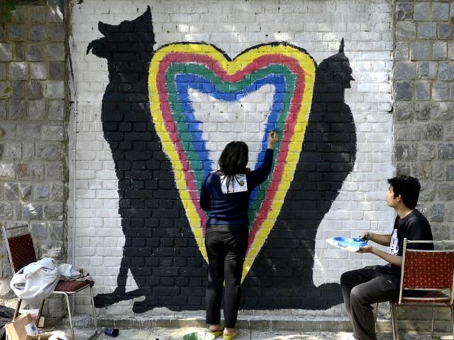 An artist walk past wall paintings created during the 'Design The Change' wall art event in New Delhi. The activity brought together more than 500 professional and budding artists on the same platform to create the wall art. AFP