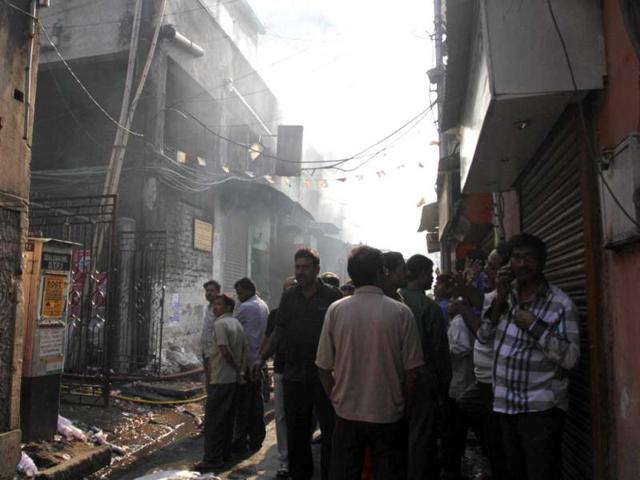 Residents and onlookers wait outside the buildings where a fire broke out at an illegal six-story plastics market in Kolkata. AP photo