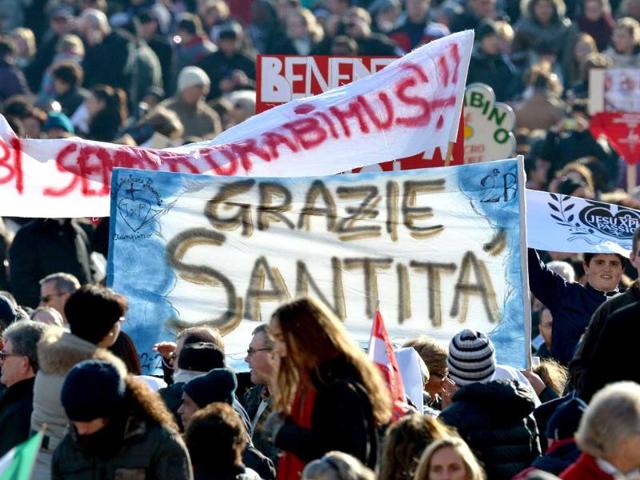 Faithful wave flags on St Peter's square ahead of Pope Benedict XVI last weekly audience. Benedict will receive the title of "Roman pontiff emeritus" and can still be addressed as "Your Holiness" and wear the white papal cassock after he officially steps down. AFP/Gabriel Bouys