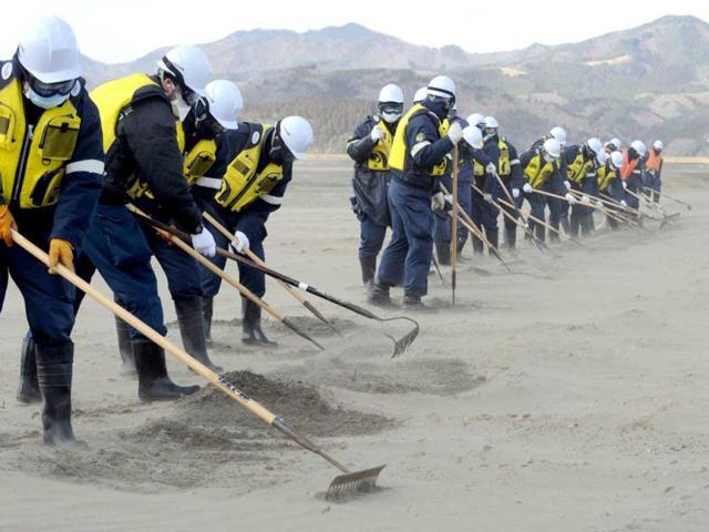 Police officers search for tsunami victims two years after, at a mud-covered riverside field near the Okawa elementary school in Ishinomaki city, Miyagi prefecture. AFP Photo