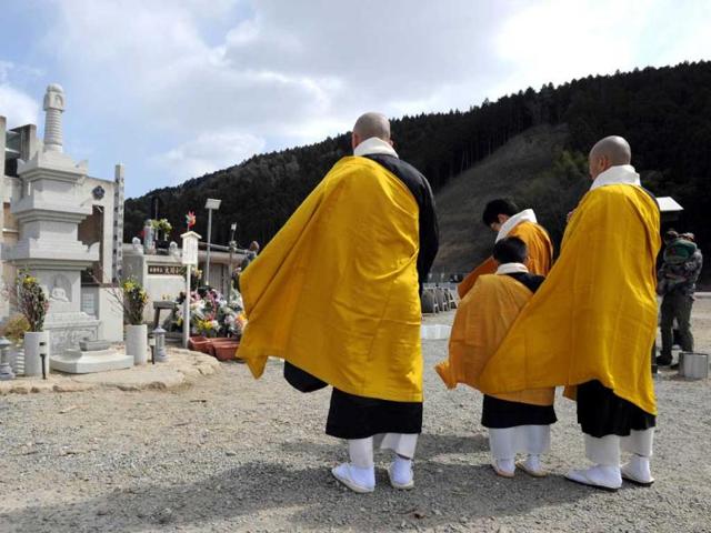 A group of buddhist monks recites the sutra at the memorial alter at the Okawa elementary school in Ishinomaki city, Miyagi prefecture. AFP Photo
