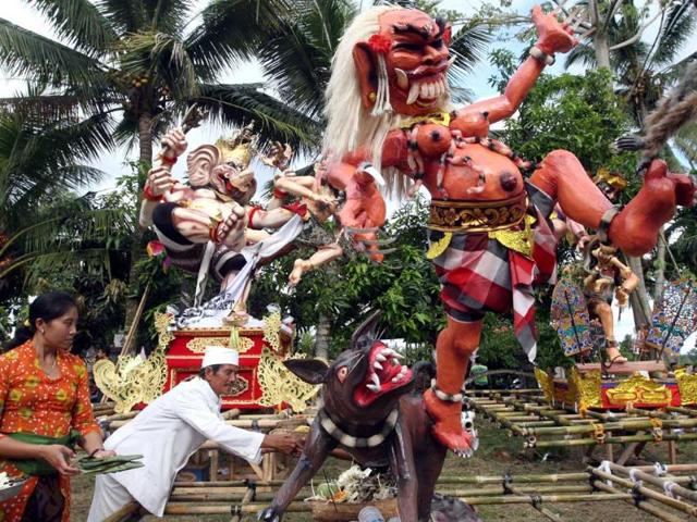 A Balinese priest puts an offering at "Ogoh-ogoh", a paper-mache effigy that symbolizes Balinese Hinduism’s mythical demons and monsters, during a parade to celebrate "Nyepi", or Bali's Day of Silence, in Ubud, Bali. AP
