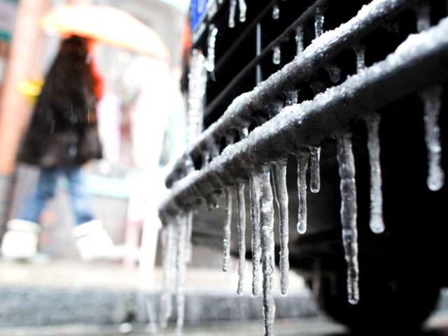 A woman with umbrella passes a car with icicles in Duesseldorf, Germany. (AP)