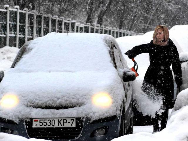 A woman removes snow from her car in the Belarus capital Minsk. (AFP)