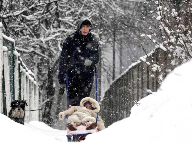 A woman walks with a child and dog in a snow covered park in the Belarus capital Minsk. (AFP)