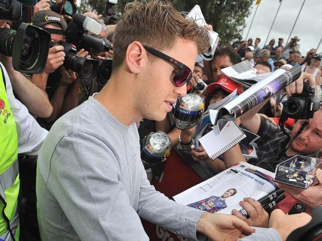 Red Bull driver Sebastian Vettel (L) of Germany signs autgraphs in the lead up to the Formula One Australian Grand Prix in Melbourne. (AFP Photo)
