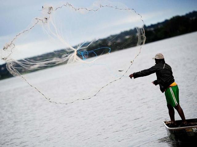A fisherman throws a fishing net into Paranoa Lake, in Brasilia on World Water Day. (AFP)