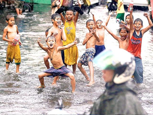 Children play at a flooded street following a sudden downpour as the world marks World Water Day in Manila, Philippines. (AP)