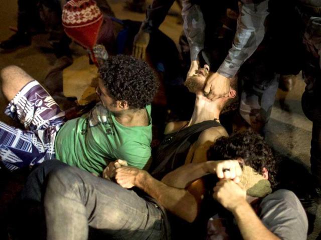 A police officer grabs a supporter of Indians occupying the old Indian Museum from under his jaw as the protesters block the road outside the museum in Rio de Janeiro. (AP)