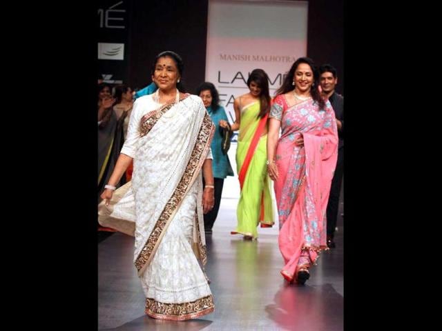 Singer Asha Bhosle (L) and film actress Hema Malini (R) showcase creations by designer Manish Malhotra during a fashion show on the first day of Lakme Fashion Week (LFW) Summer/Resort 2013. (AP Photo)