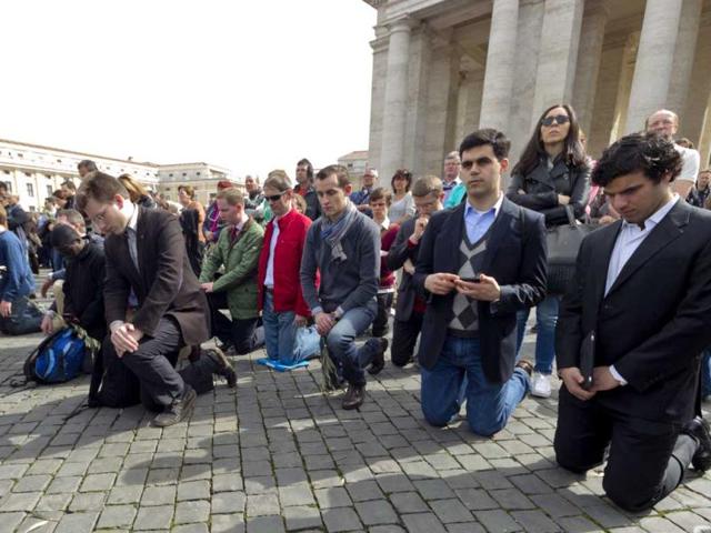 The faithful kneel as they join Pope Francis in prayer on Palm Sunday at the Vatican. AP