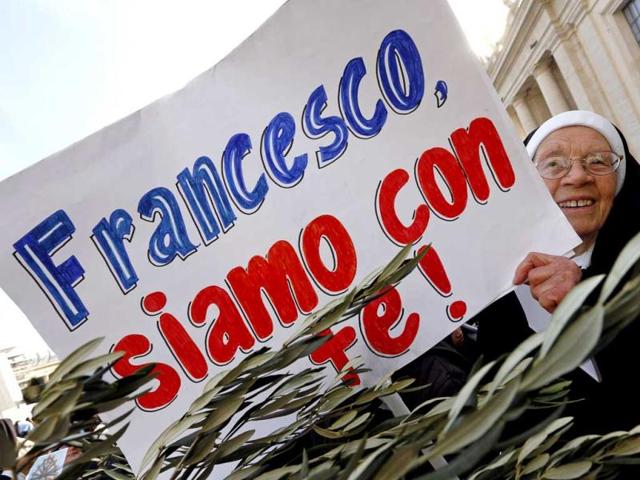 A nun holds a placard as she waits for Pope Francis at the Palm Sunday mass at Saint Peter's Square. The placard reads, "Francesco, we are with you". Reuters
