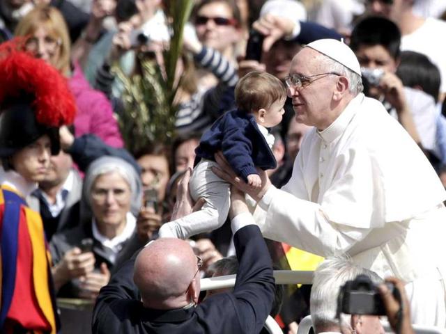 Pope Francis kisses a child after the Palm Sunday mass at Saint Peter's Square at the Vatican. Reuters