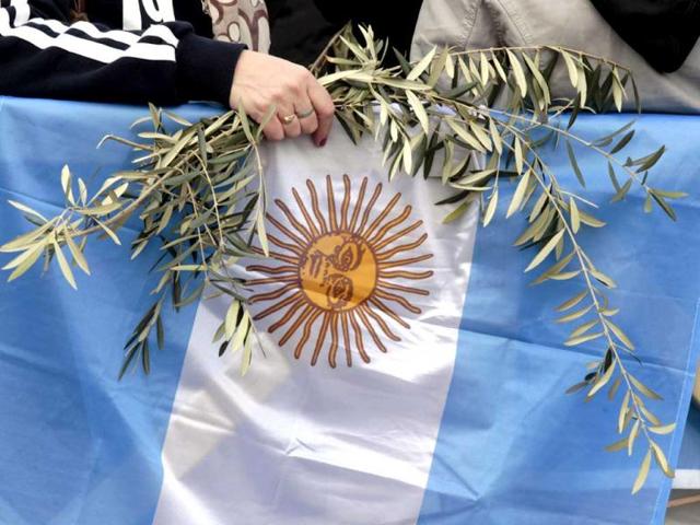 A faithful holds olive branches and an Argentine flag as Pope Francis celebrates his first Palm Sunday Mass in St. Peter's Square at the Vatican. AP