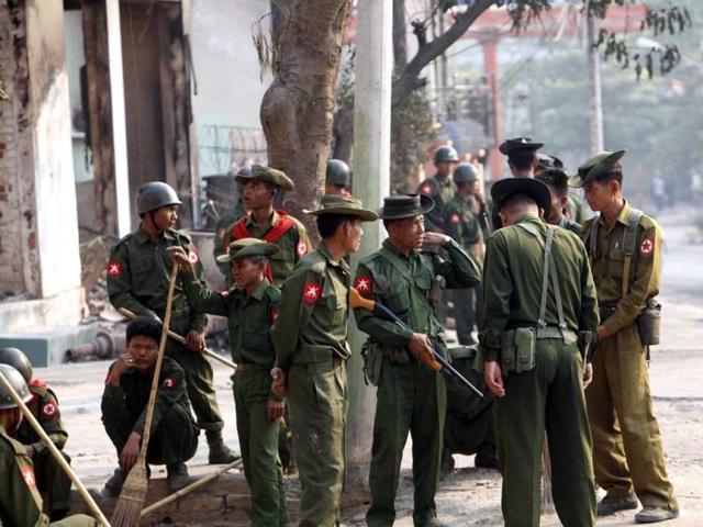 Myanmar soldiers take a break as they remove debris from destroyed buildings and others provide security, following the ethnic unrest between Buddhists and Muslim, in Meikhtila, in Myanmar. AP Photo
