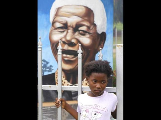 A child stands in front of Nelson Mandela's portrait in a park in Soweto, South Africa. AP/Denis Farrell