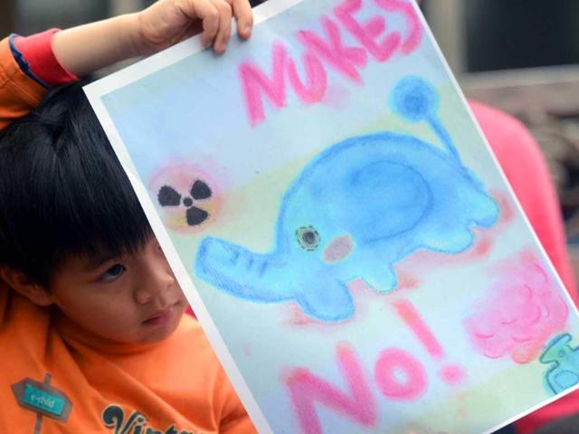 A child displays a banner during a demonstration outside Parliament in Taipei. A dozen of elementary school students led by their parents during an anti-nuclear power plant protest to mark the coming Children's day. AFP