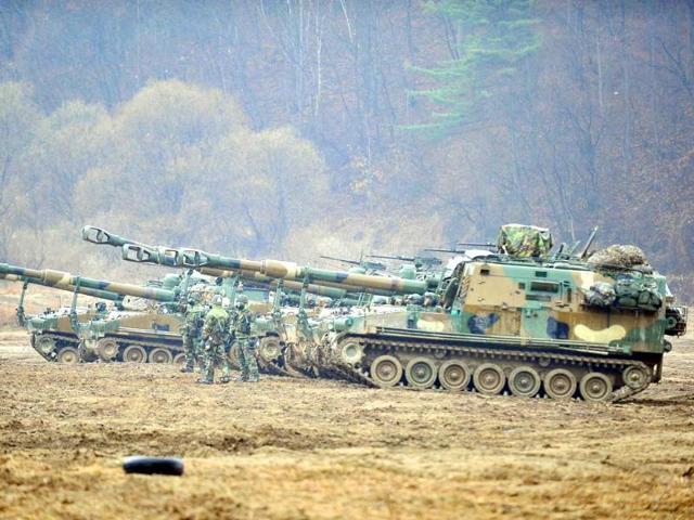 South Korean soldiers wear gas masks stand in front of K-55 self-propelled howitzers at a military training field on the border city of Paju. AFP