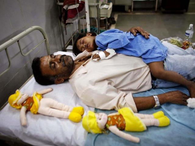 A girl who was injured during the collapse of a residential building, rests with a social worker on a hospital bed in Thane district, on the outskirts of Mumbai. (Reuters)