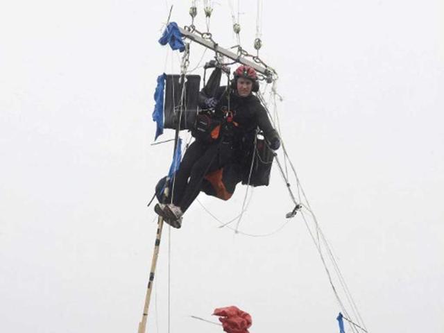 Matt Silver-Vallance drops some excess material as he flies above Table Bay, with some of his support crew in boats from Nelson Mandela's apartheid island prison using helium-filled giant party balloons in Cape Town. AFP